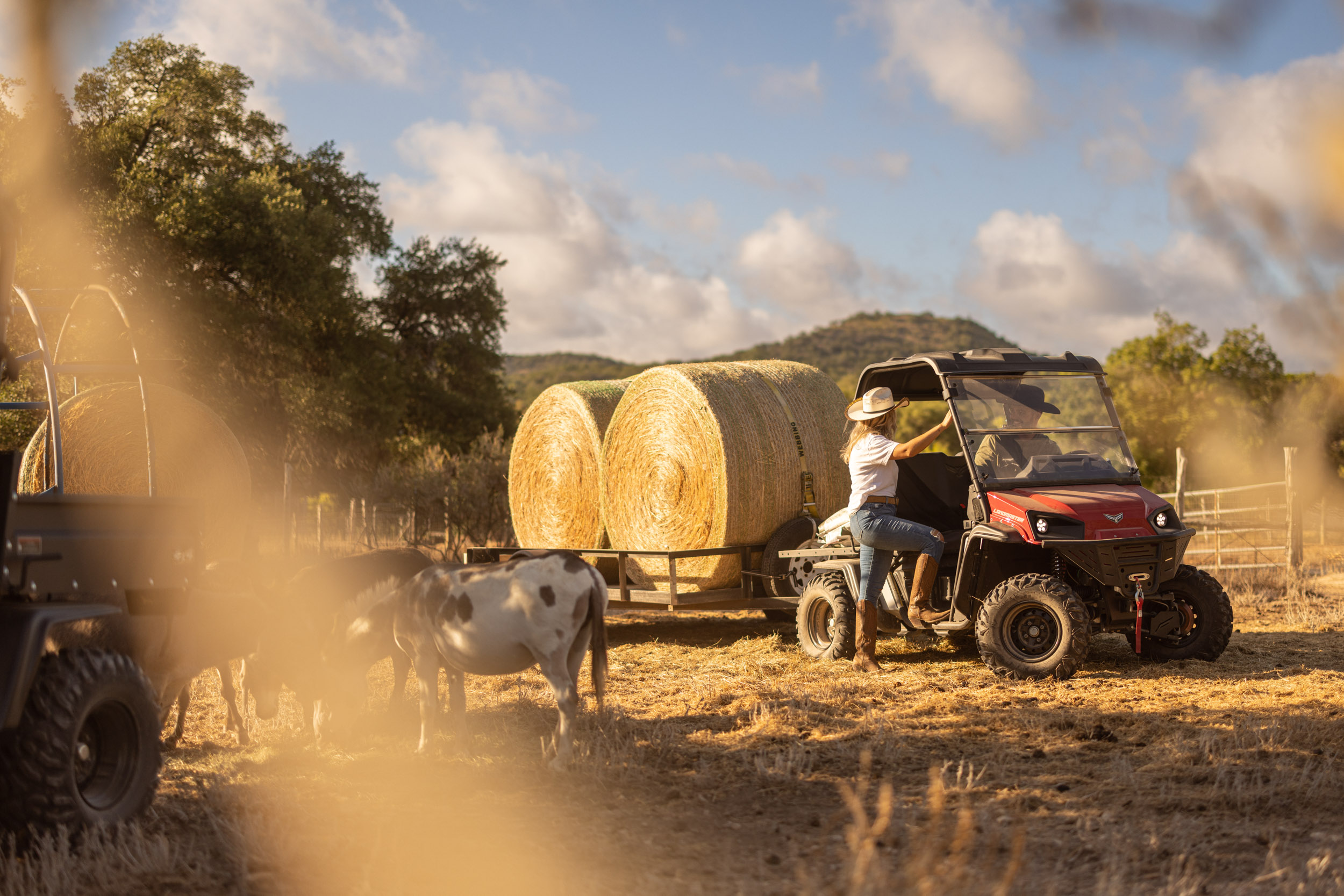 woman getting into utv towing large hay bales