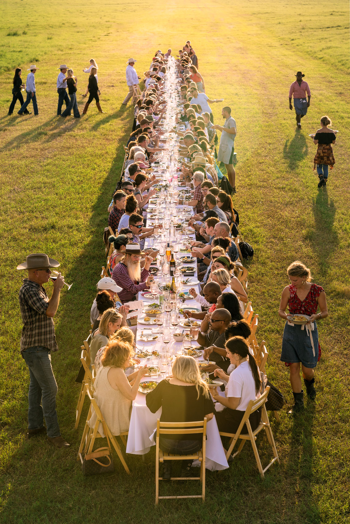 dinner table setup with people at outstanding in the field event on farm in floresville texas