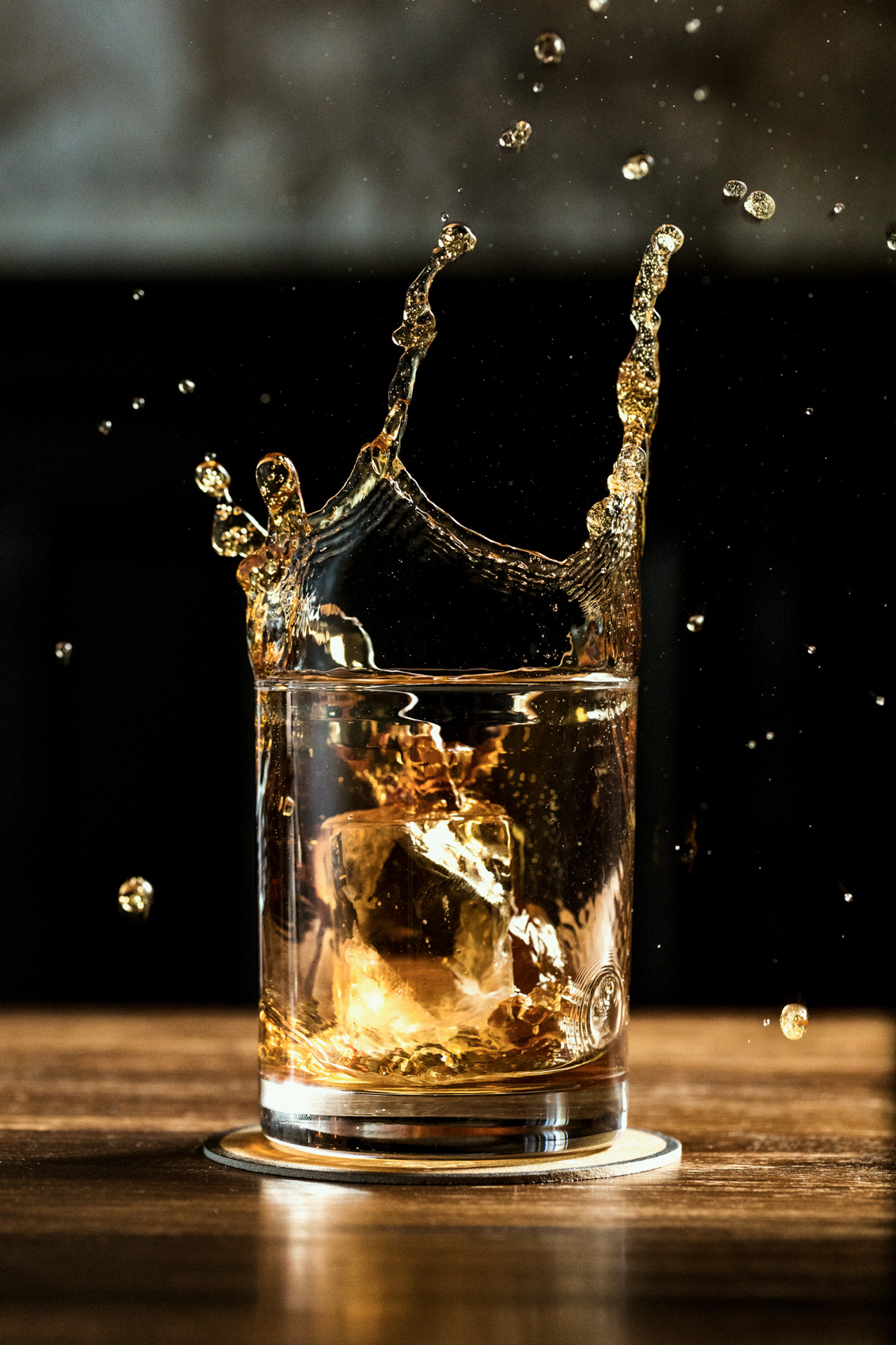 whiskey splashing from ice cube dropped in glass