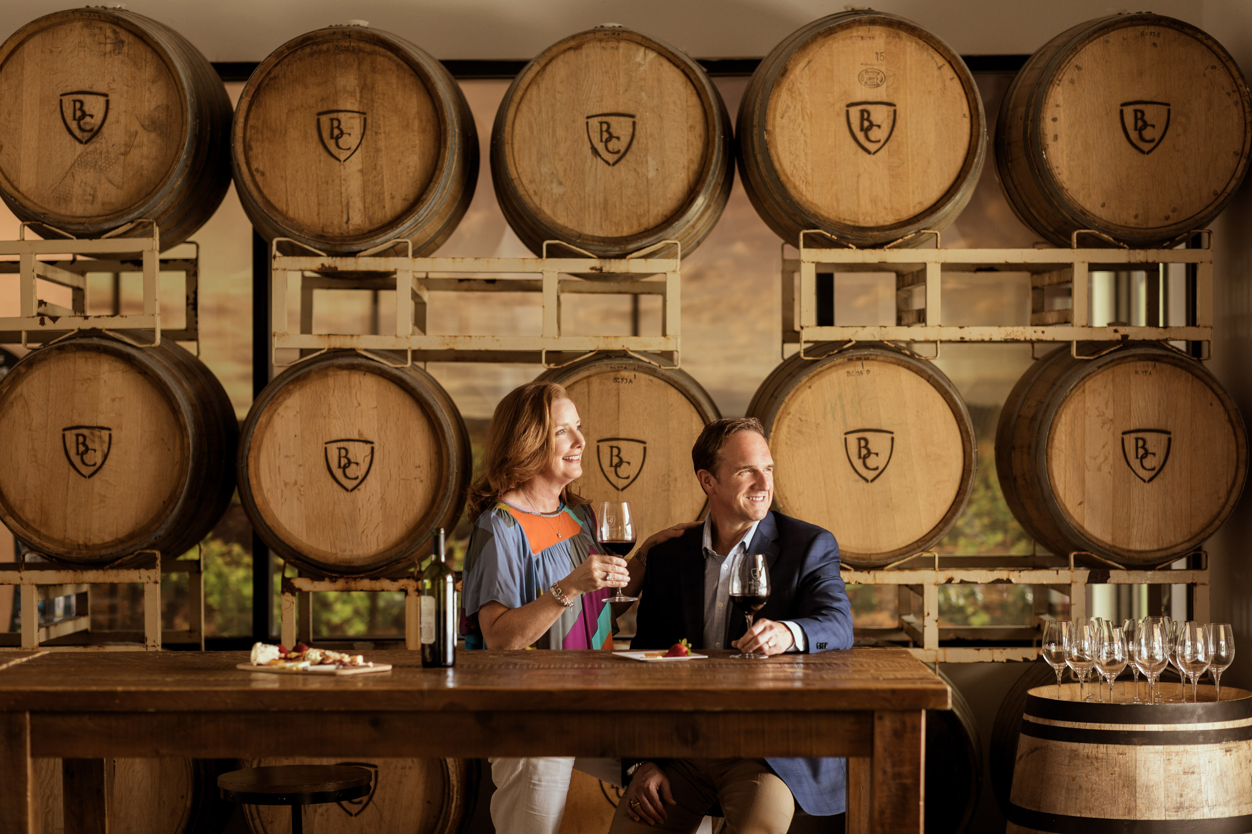 woman and man drinking wine in tasting room at winery with wine barrels