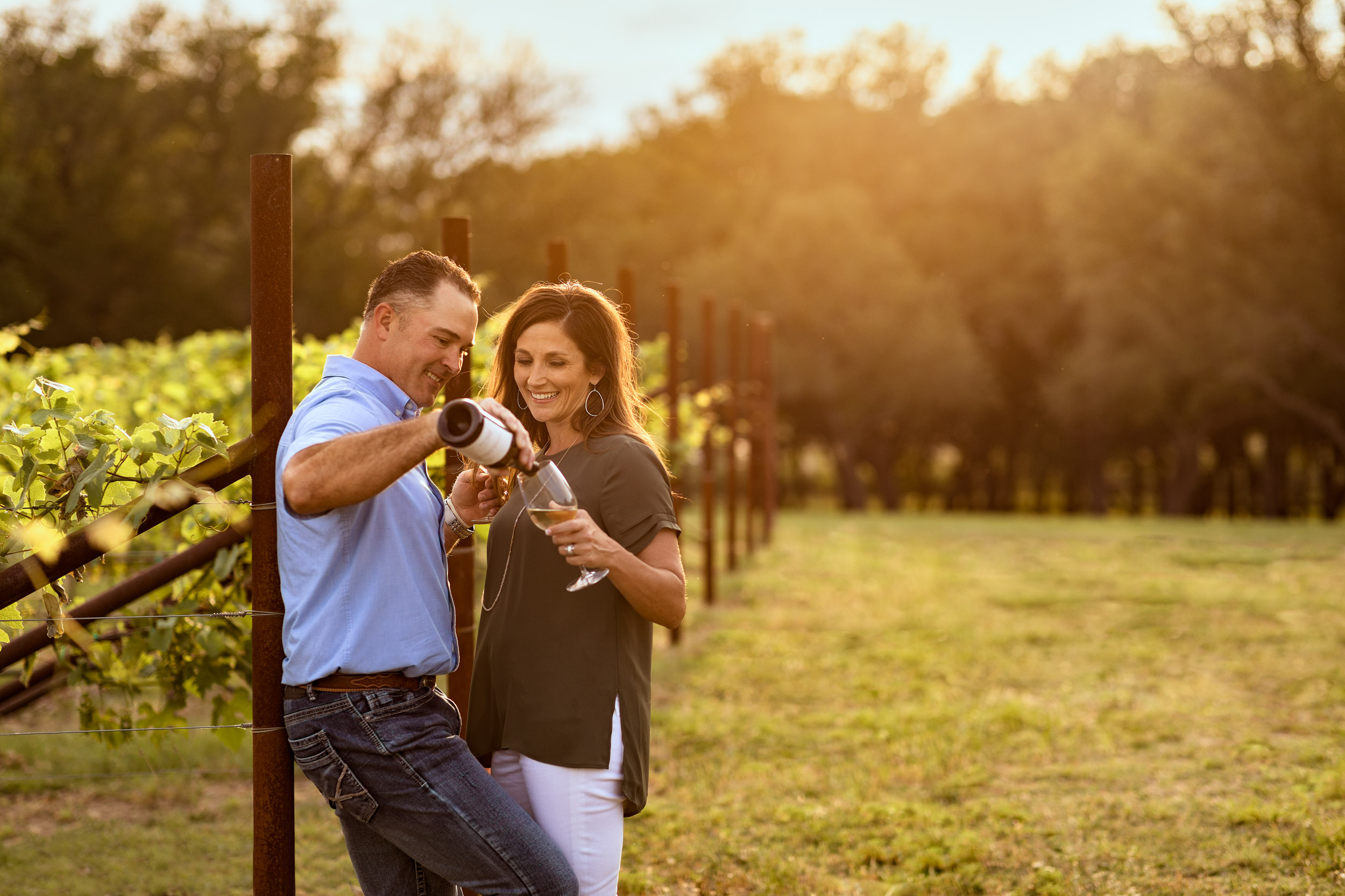 man pouring wine for woman in grape vineyard