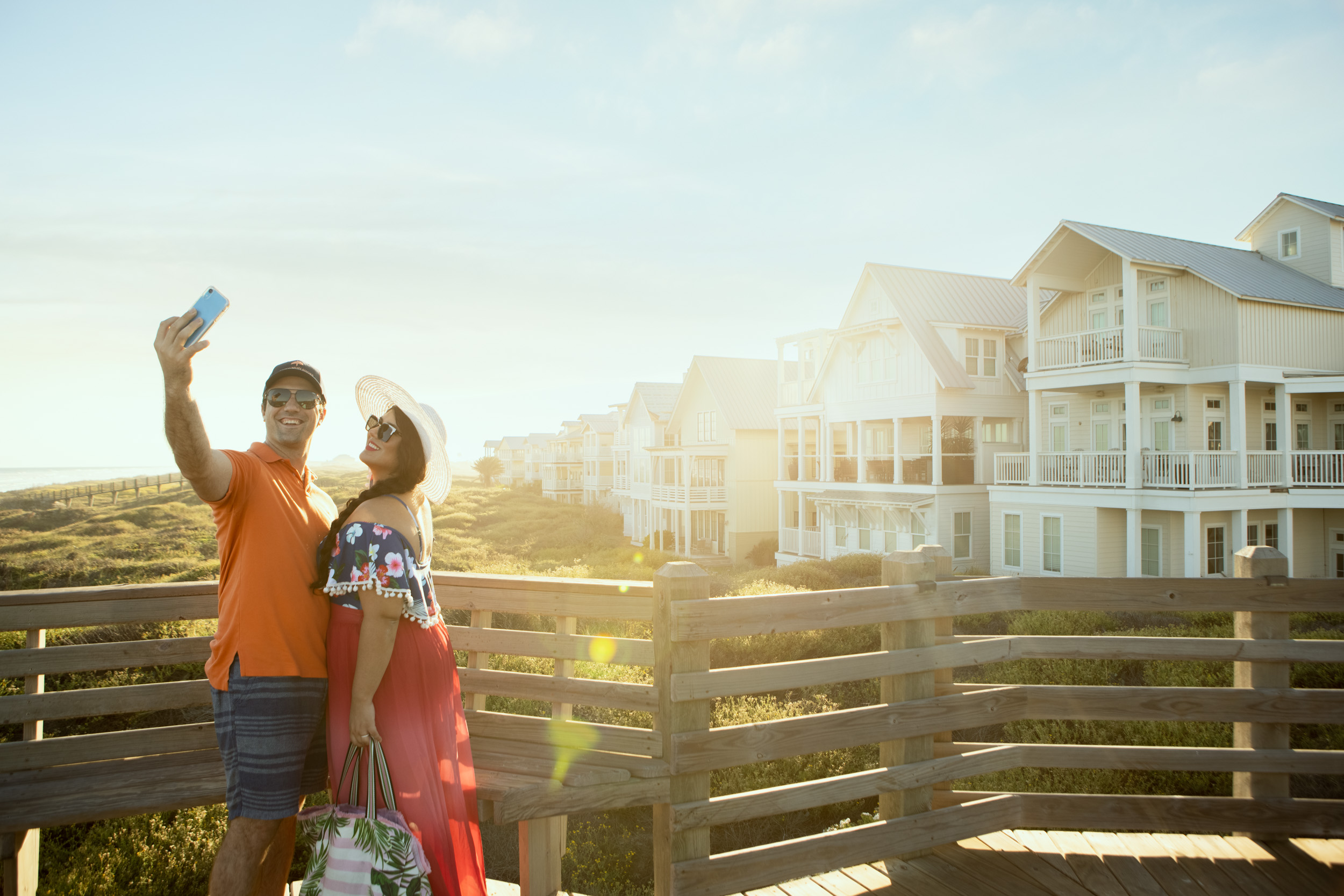 couple taking selfie photo on boardwalk with dunes and houses