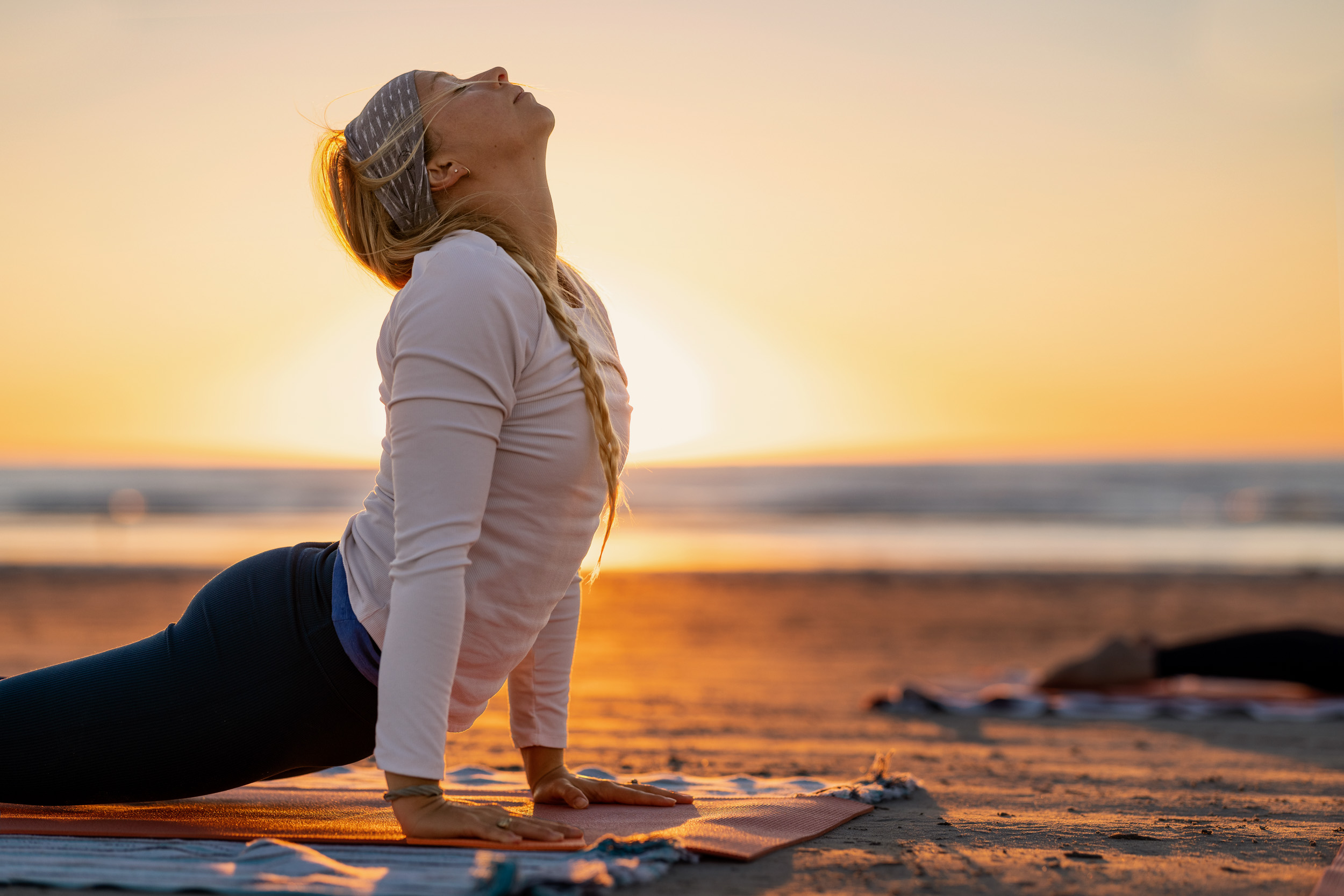 woman posing sun salutation yoga at sunrise on beach