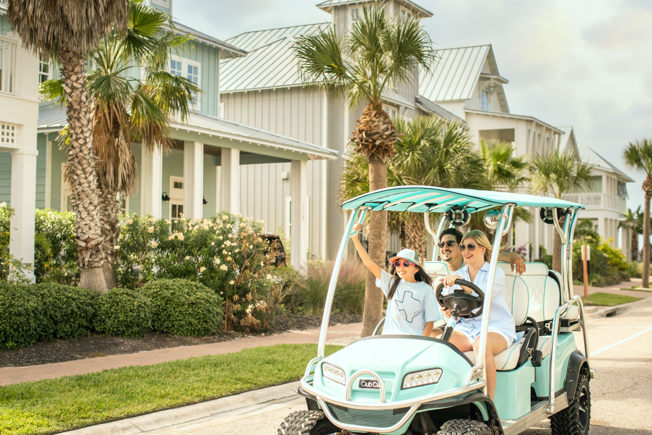 young family rides in golf cart through community with beach houses