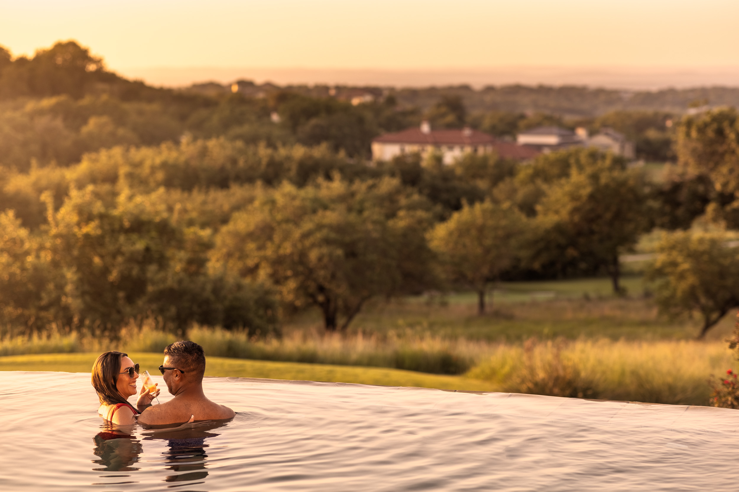 couple at edge of infinity pool with hill country at sunset