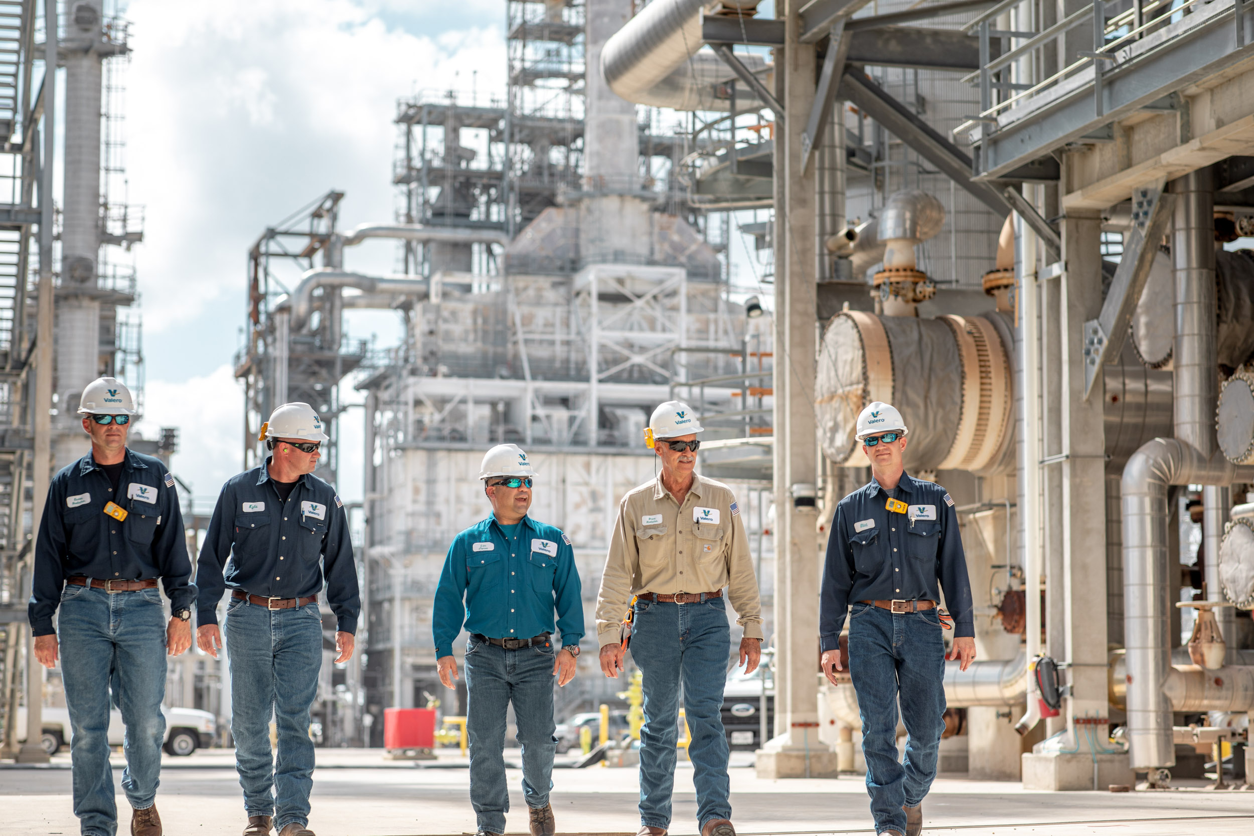 group of workers walking through oil refinery