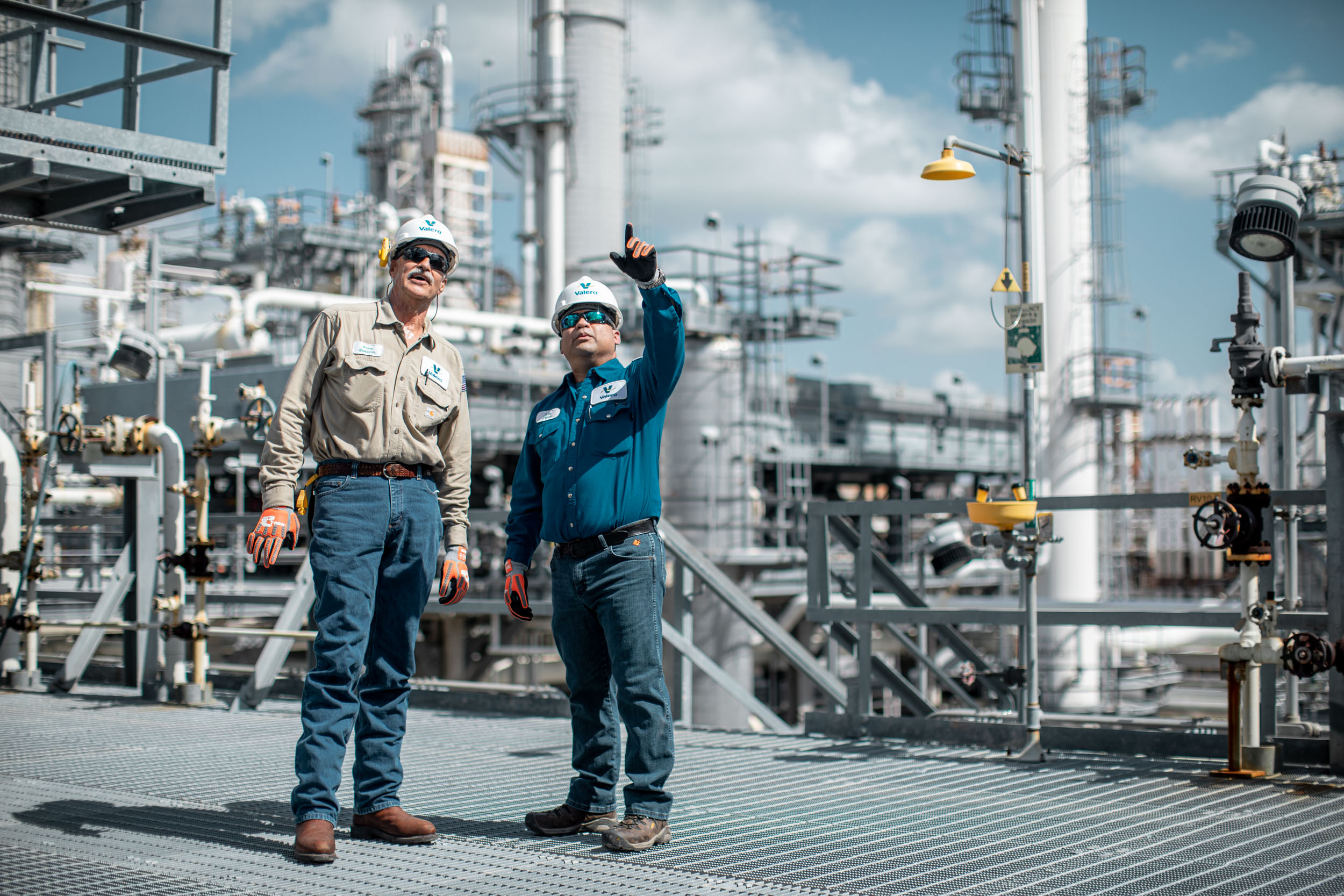 two valero employees standing on platform looking up and pointing