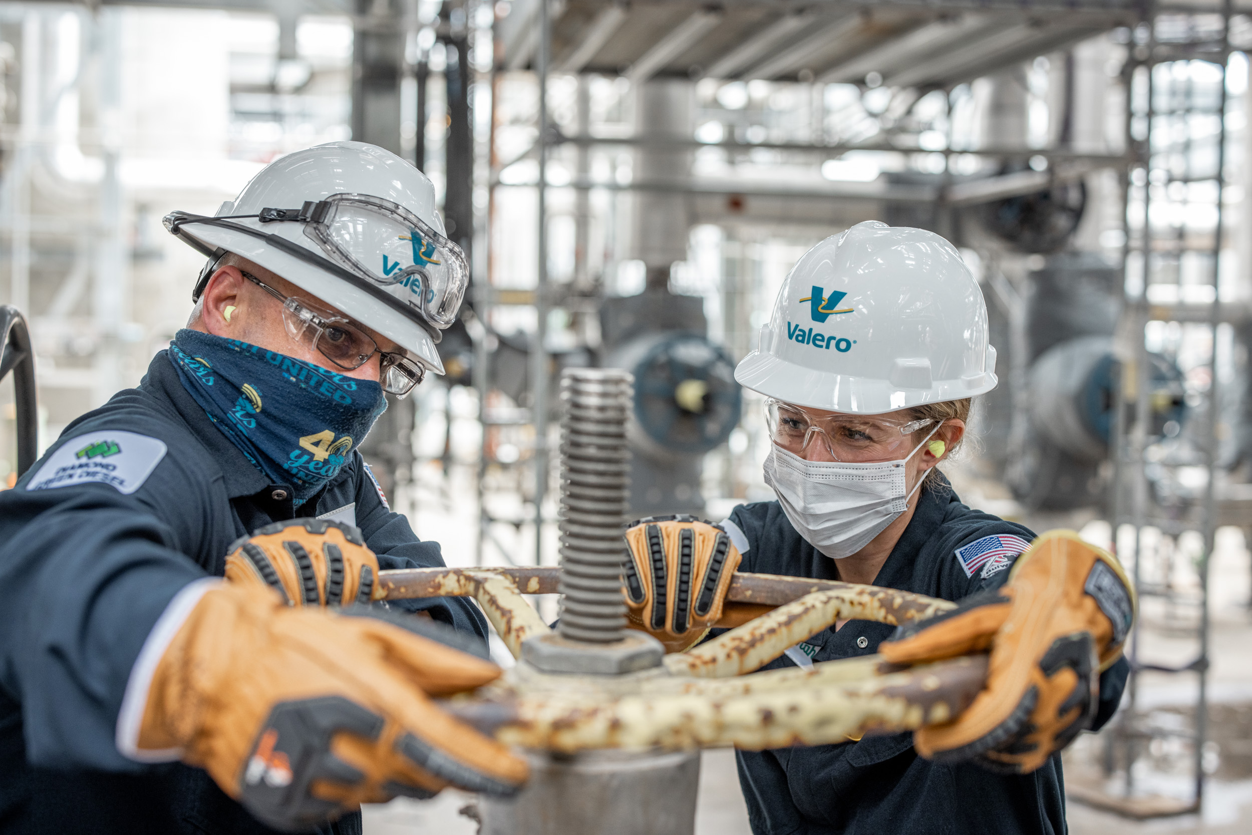 two valero oil refinery employees turning valve wheel