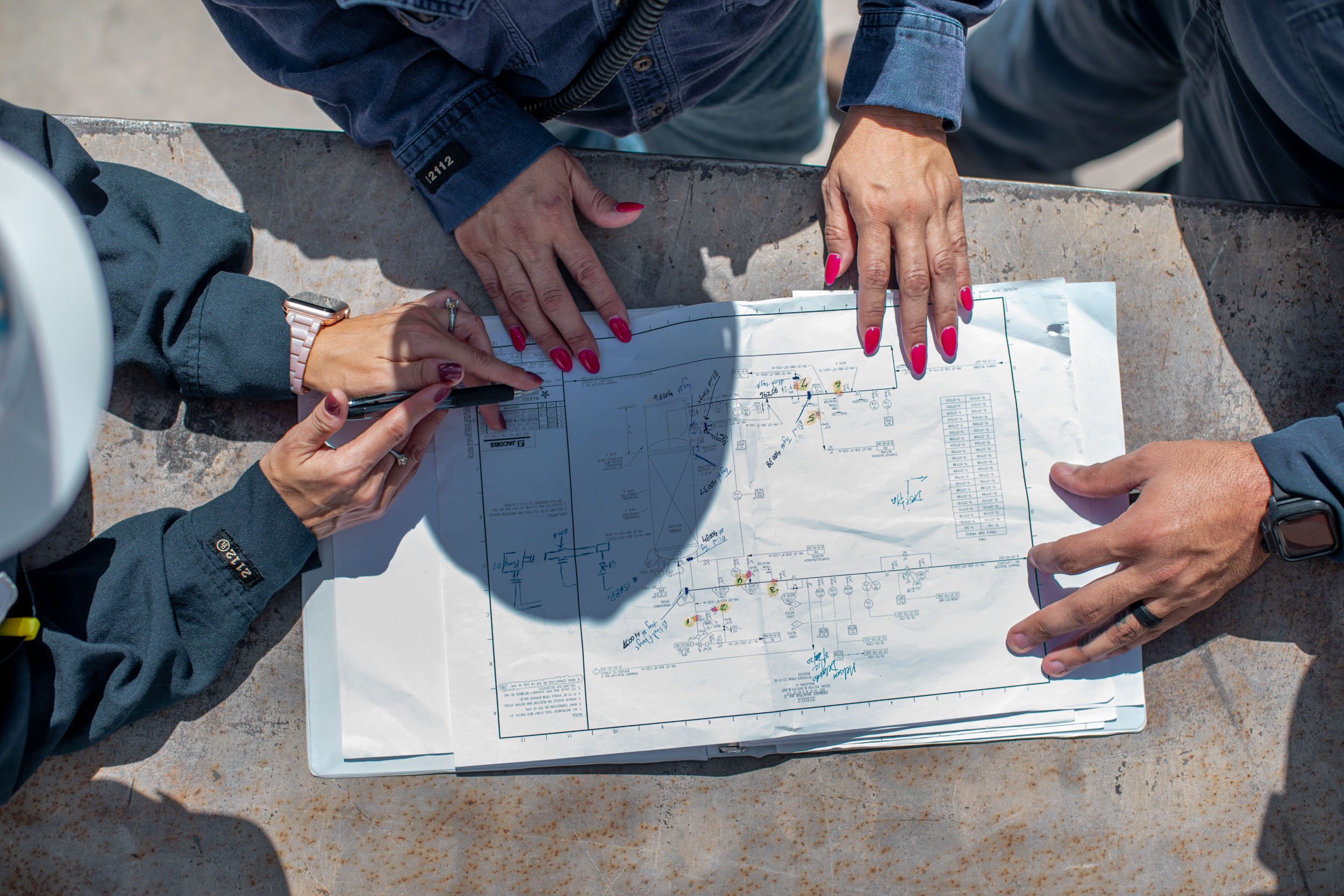 close up of blue prints and workers hands pointing at diagrams