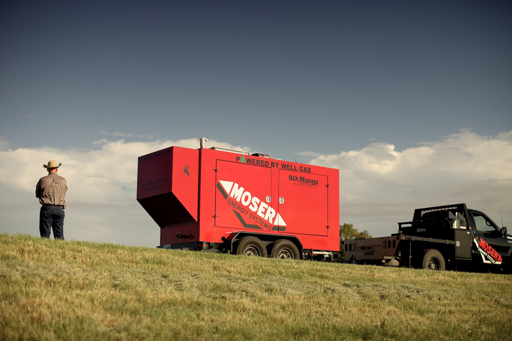 man stands on hill top with moser energy unit and truck