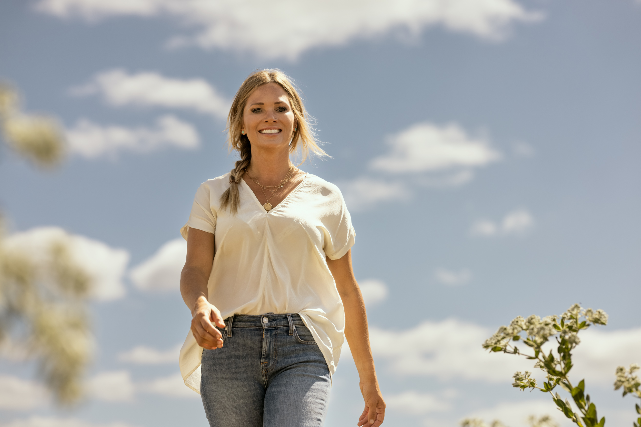 portrait of young woman wear jeans and white top walking towards camera
