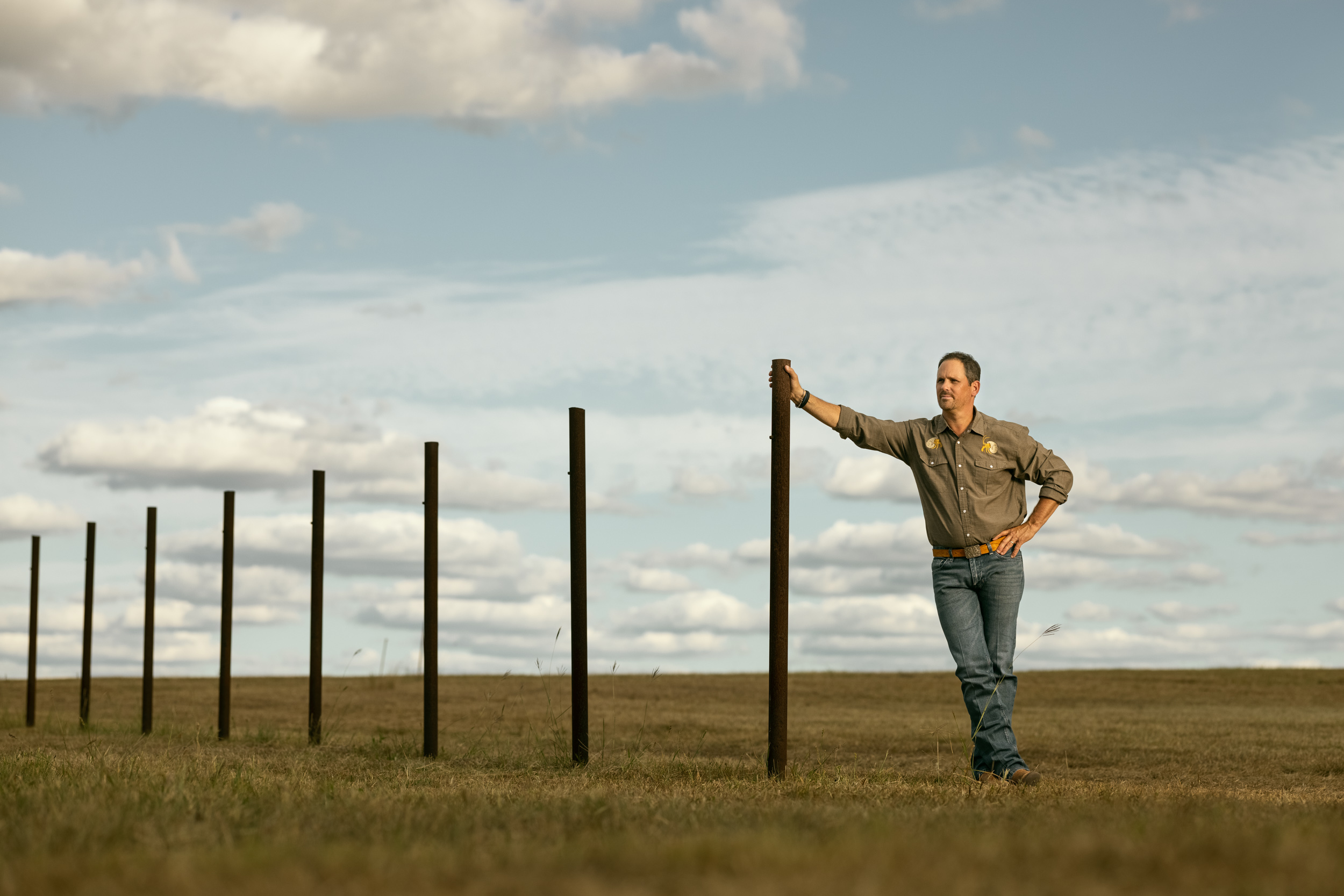 fredericksburg realtor justin cop poses on old fence post in field