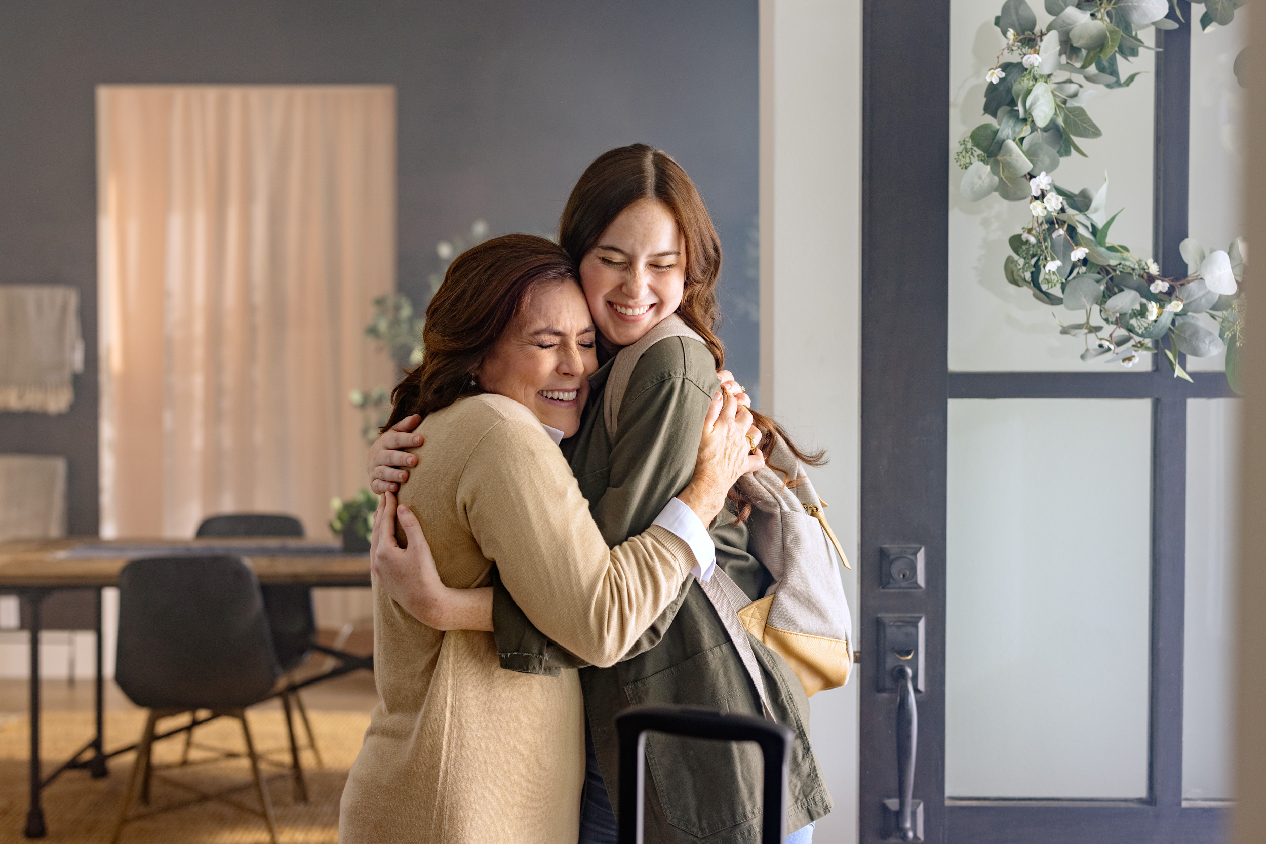 two women hug each other near doorway inside home