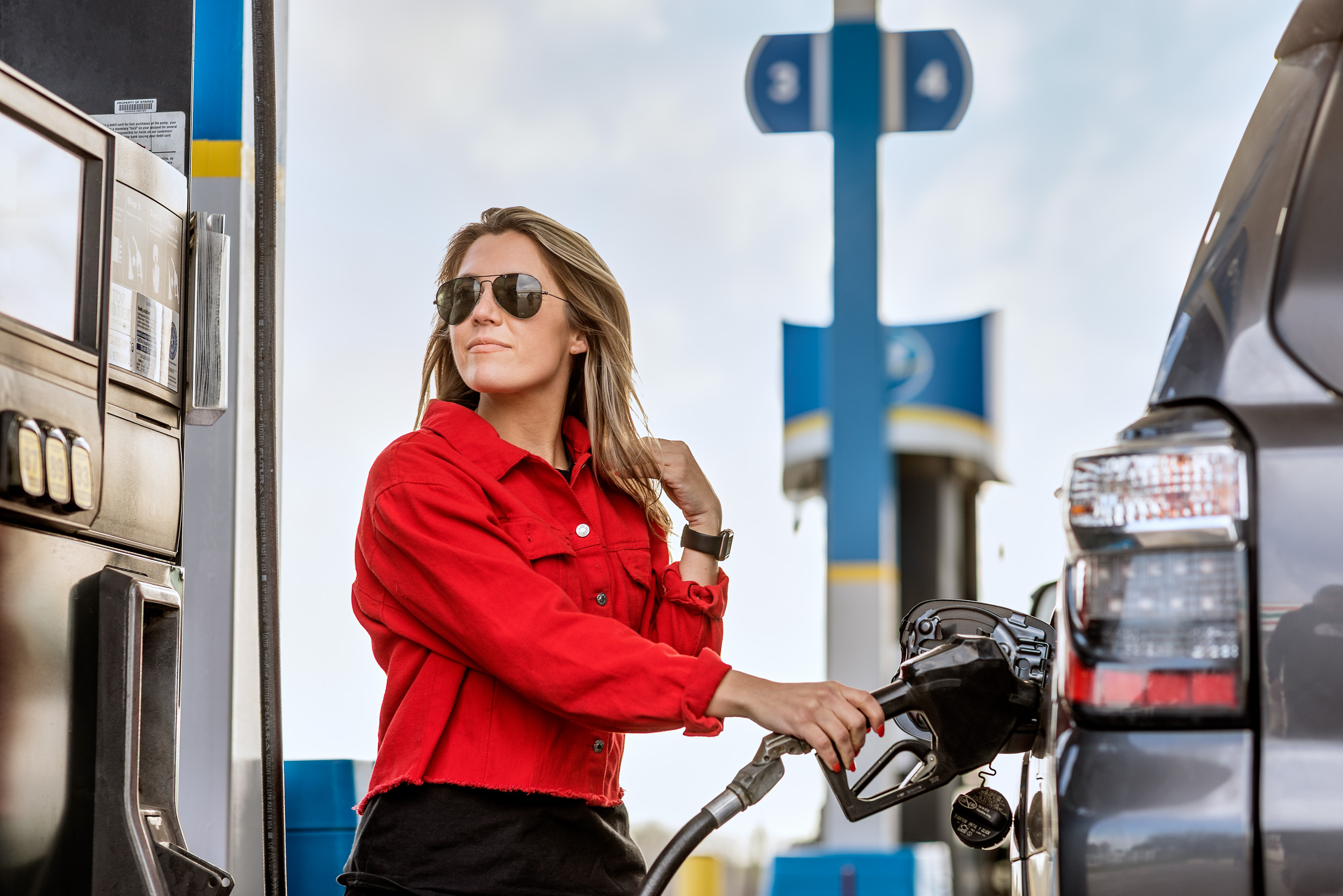 woman wearing red top pumping gas at valero gas station