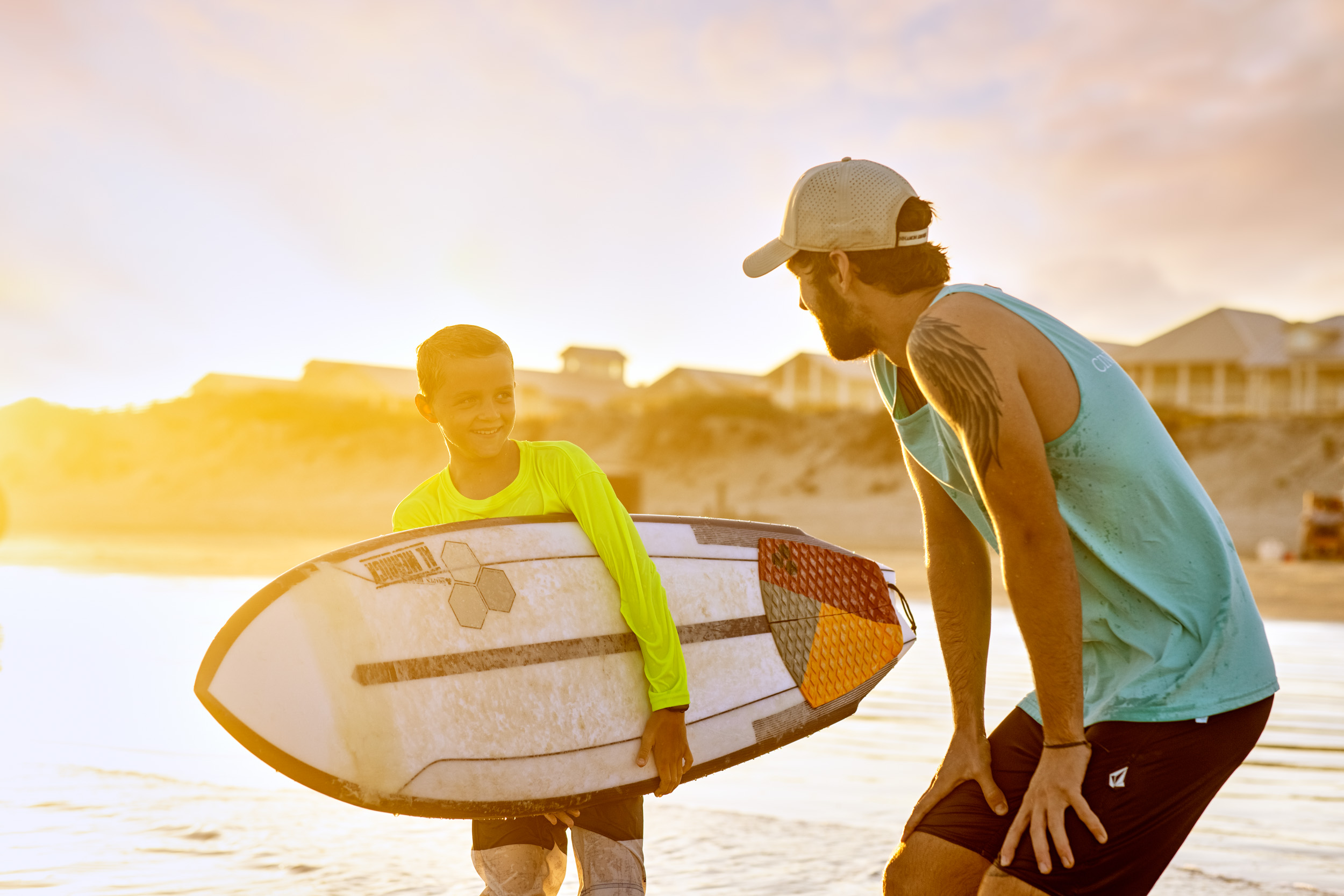surf instructor and student holding surfboard on beach