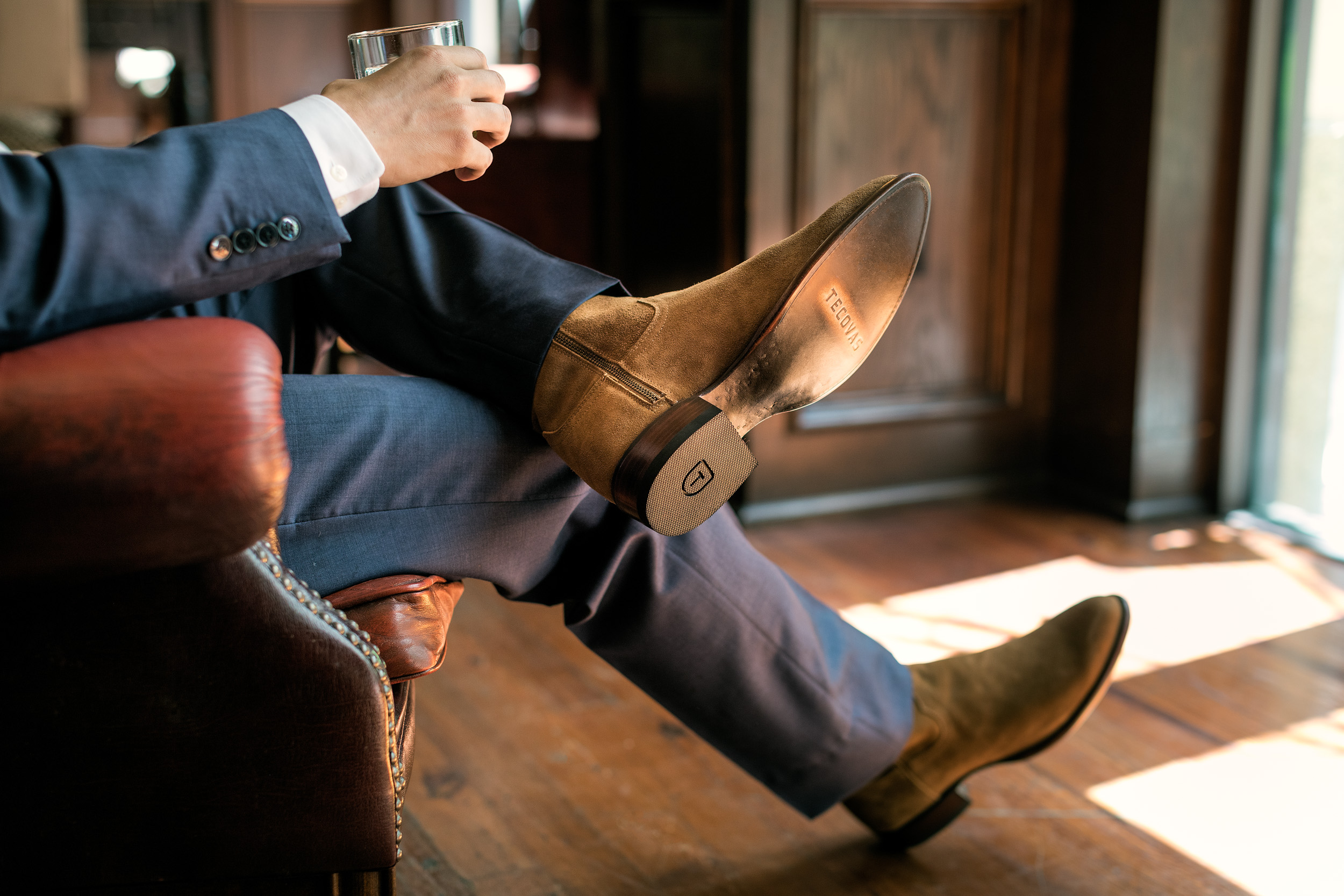 man sitting in leather chair wearing suit and tecovas cowboy boots