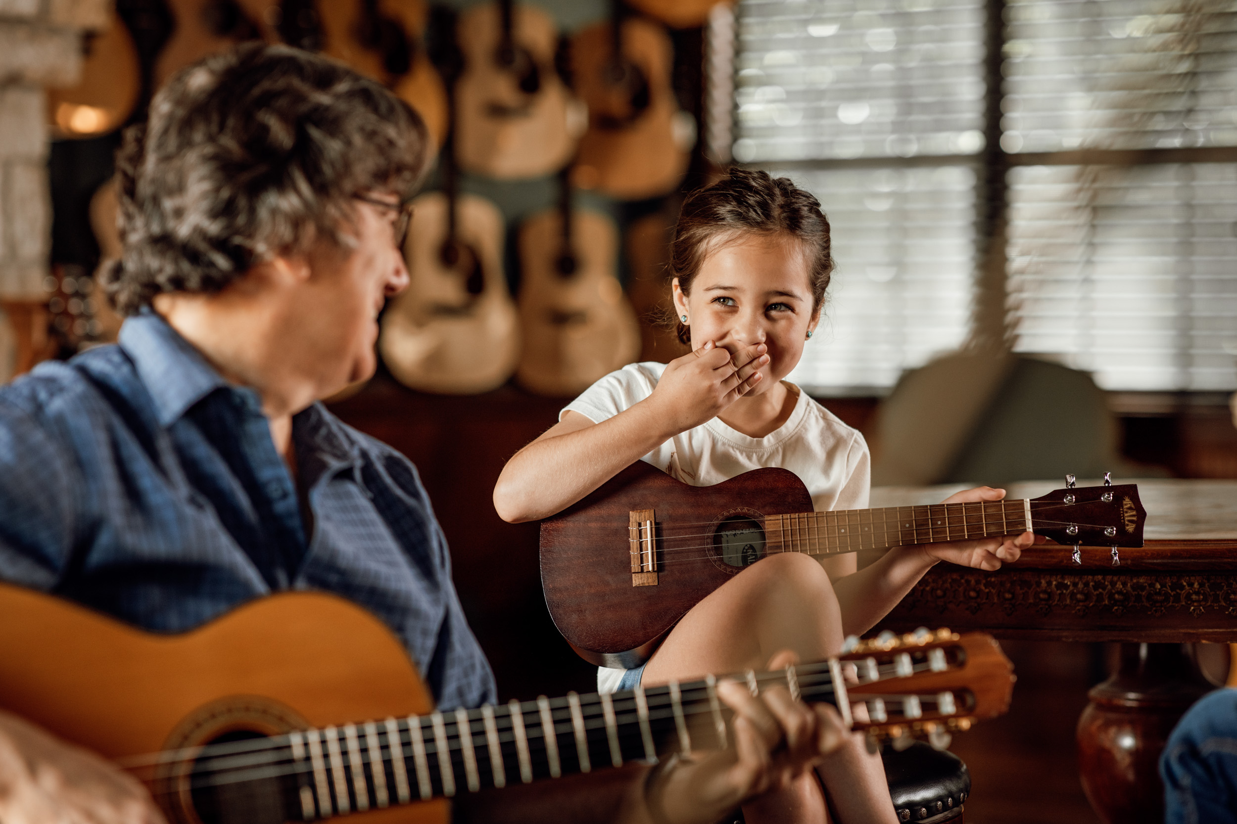 young girl guitar student laughs with instructor