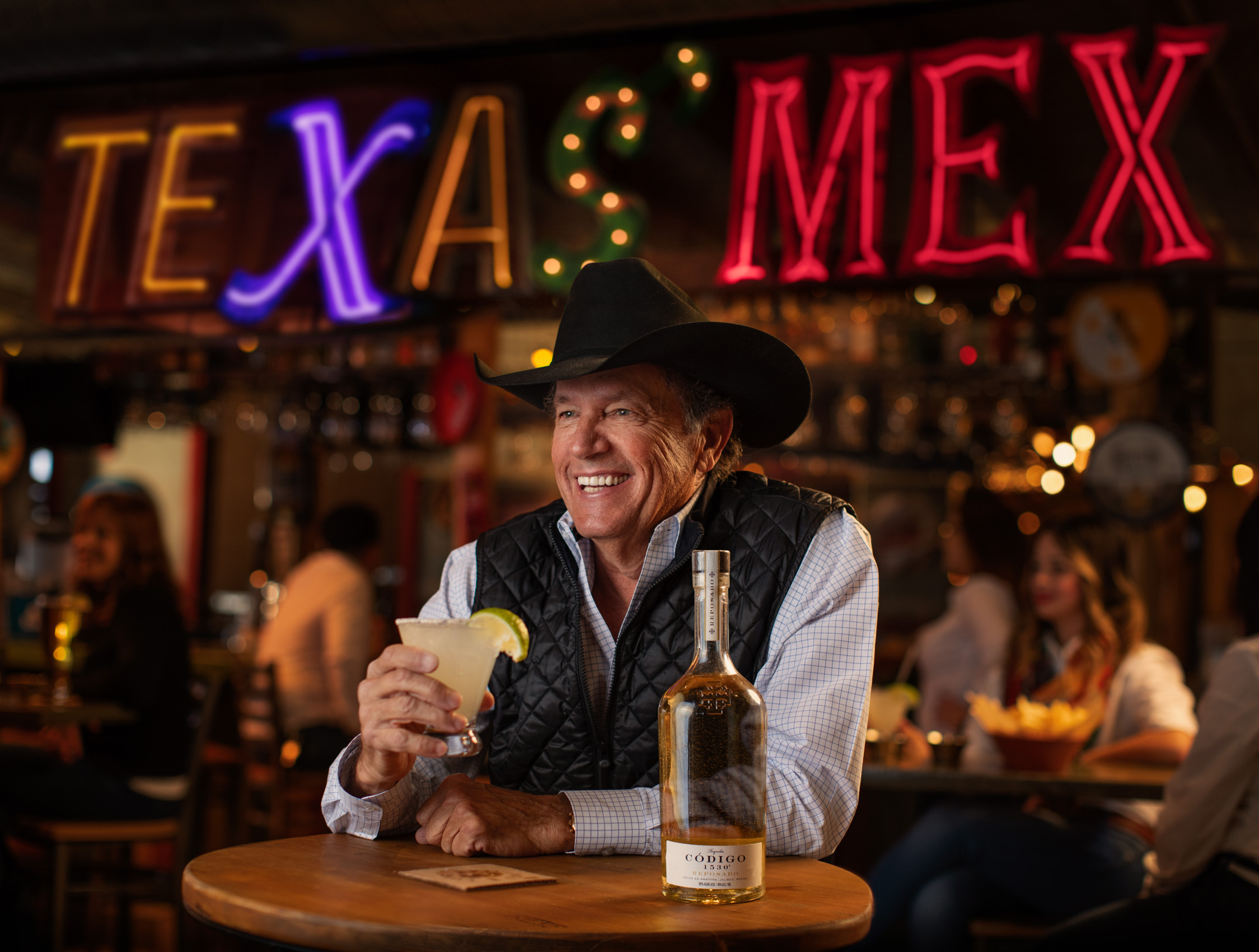 george straight holding margarita in restaurant with tex mex sign in background