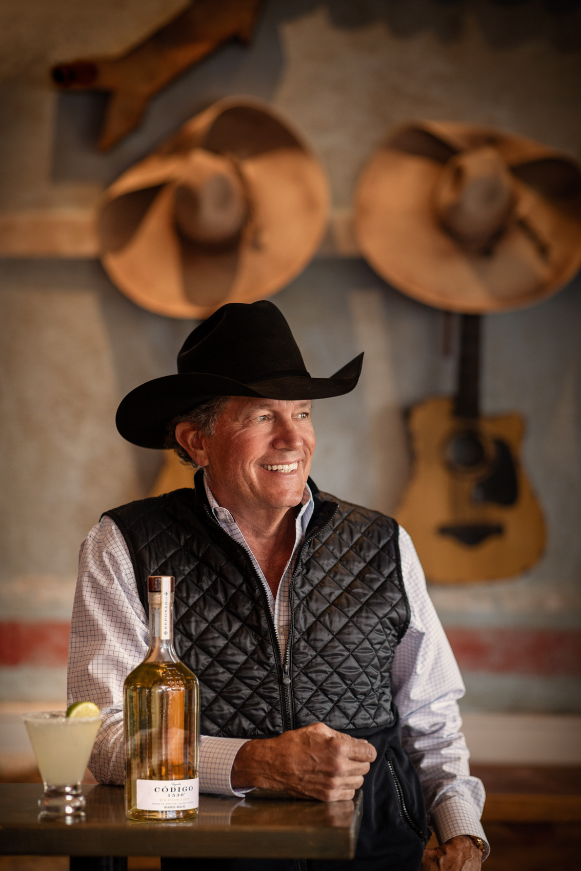 country singer george strait looking off camera with guitars and hats in background