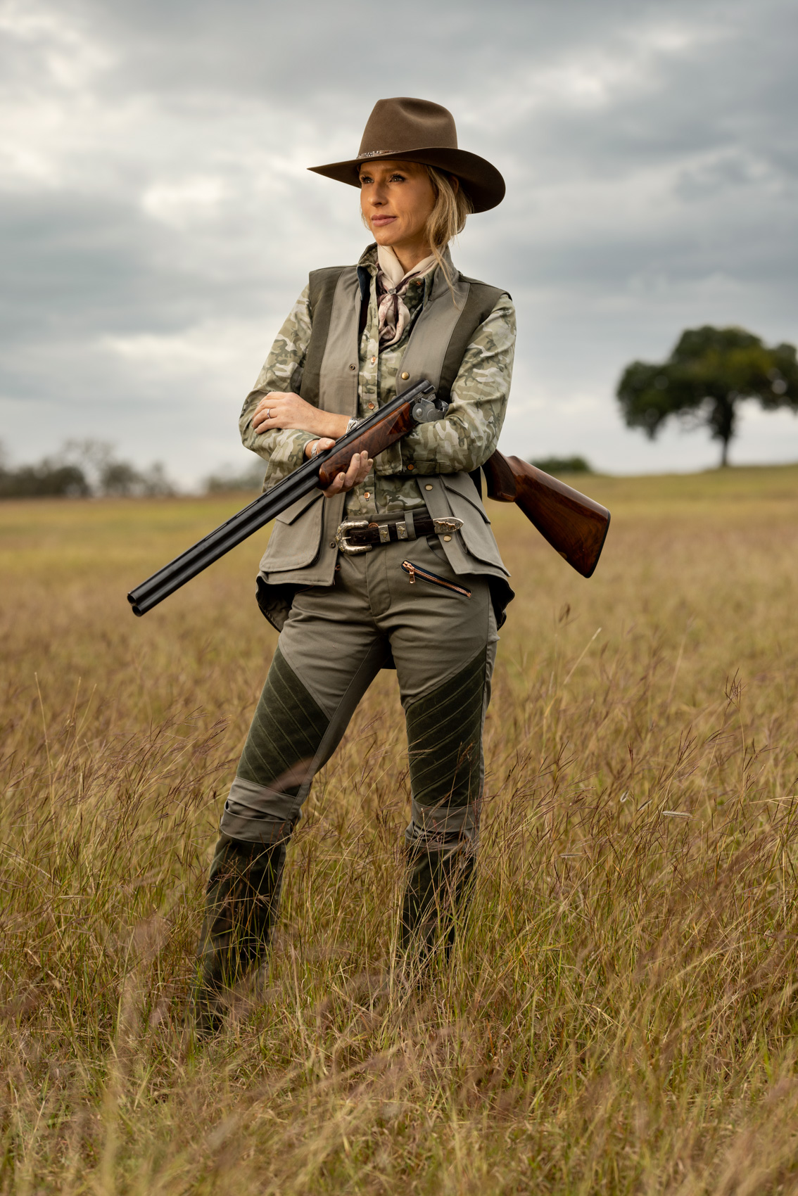 woman holding shotgun standing in field