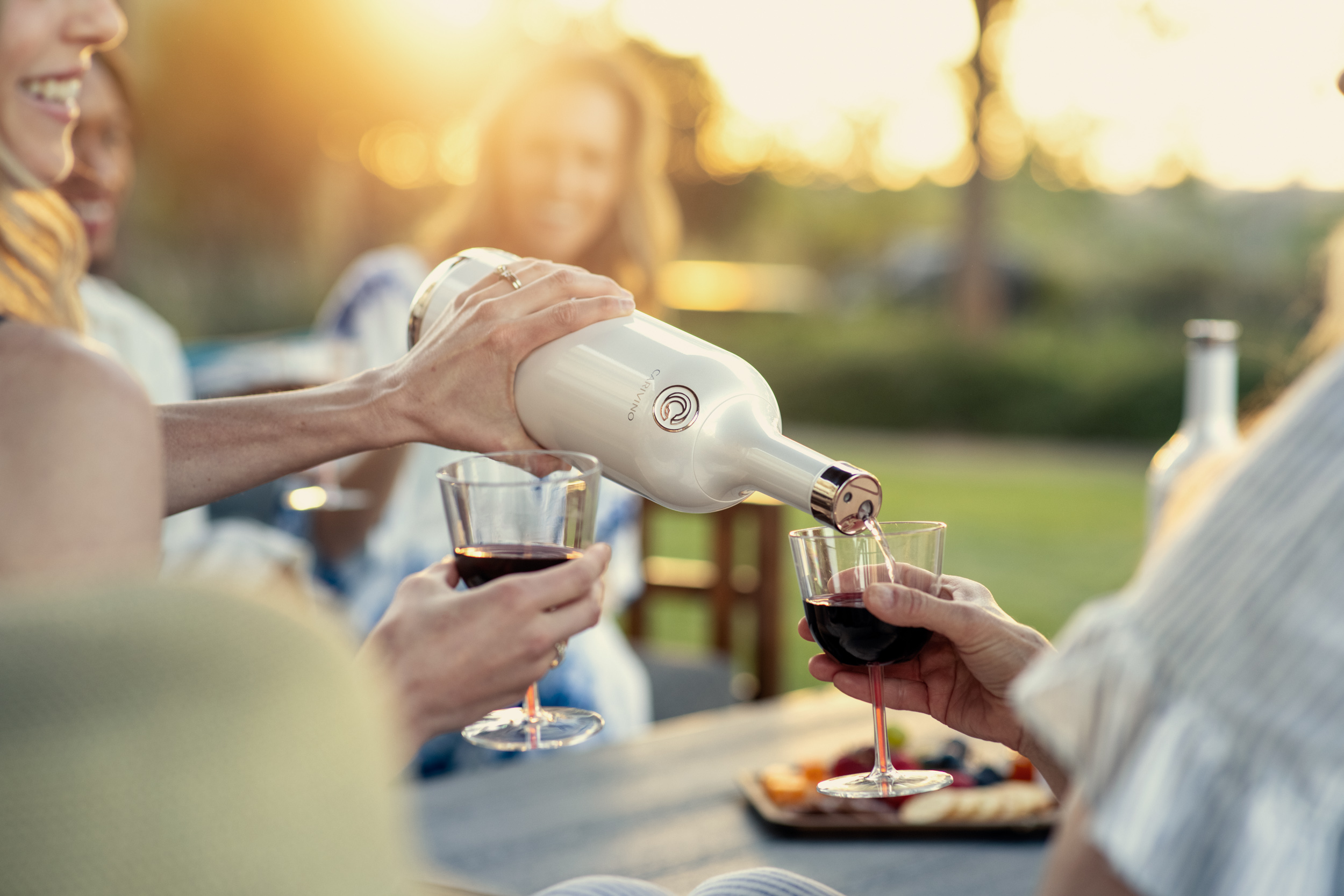 woman pouring wine from carivino with group of friends outside