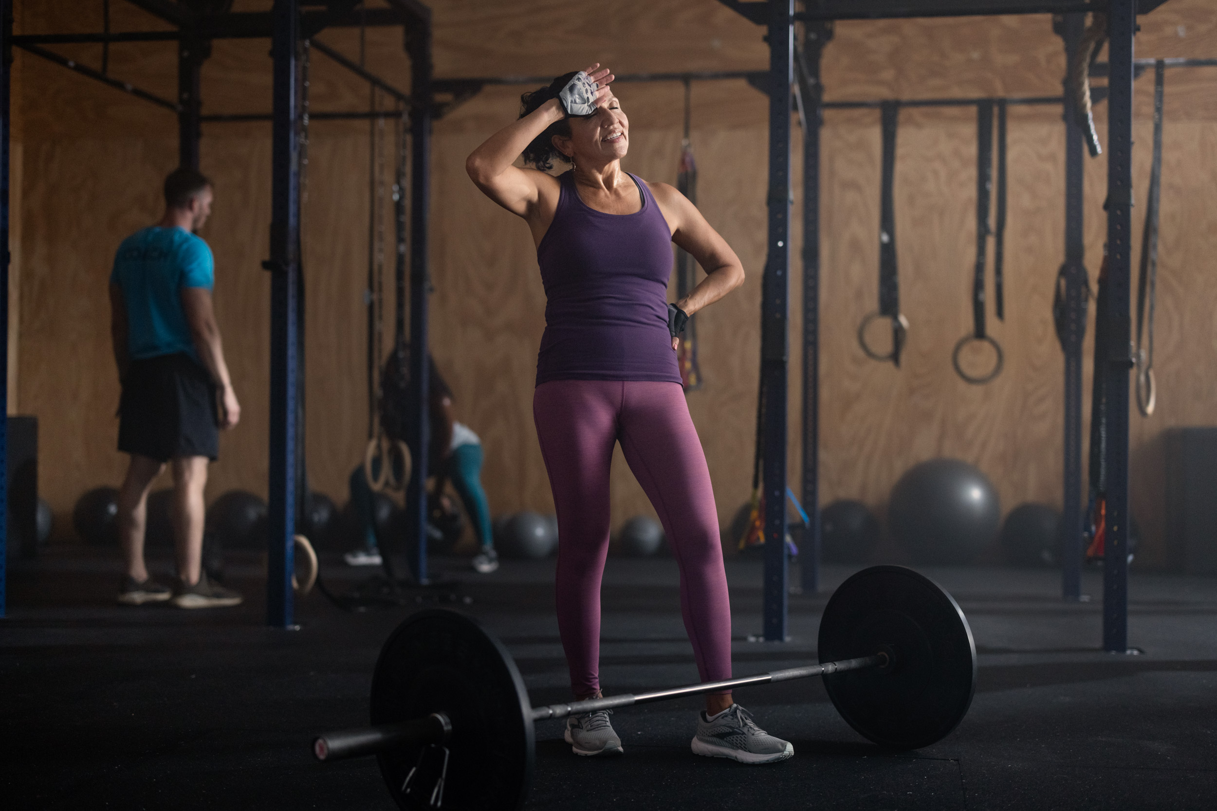 older woman resting after lifting barbell in crossfit gym