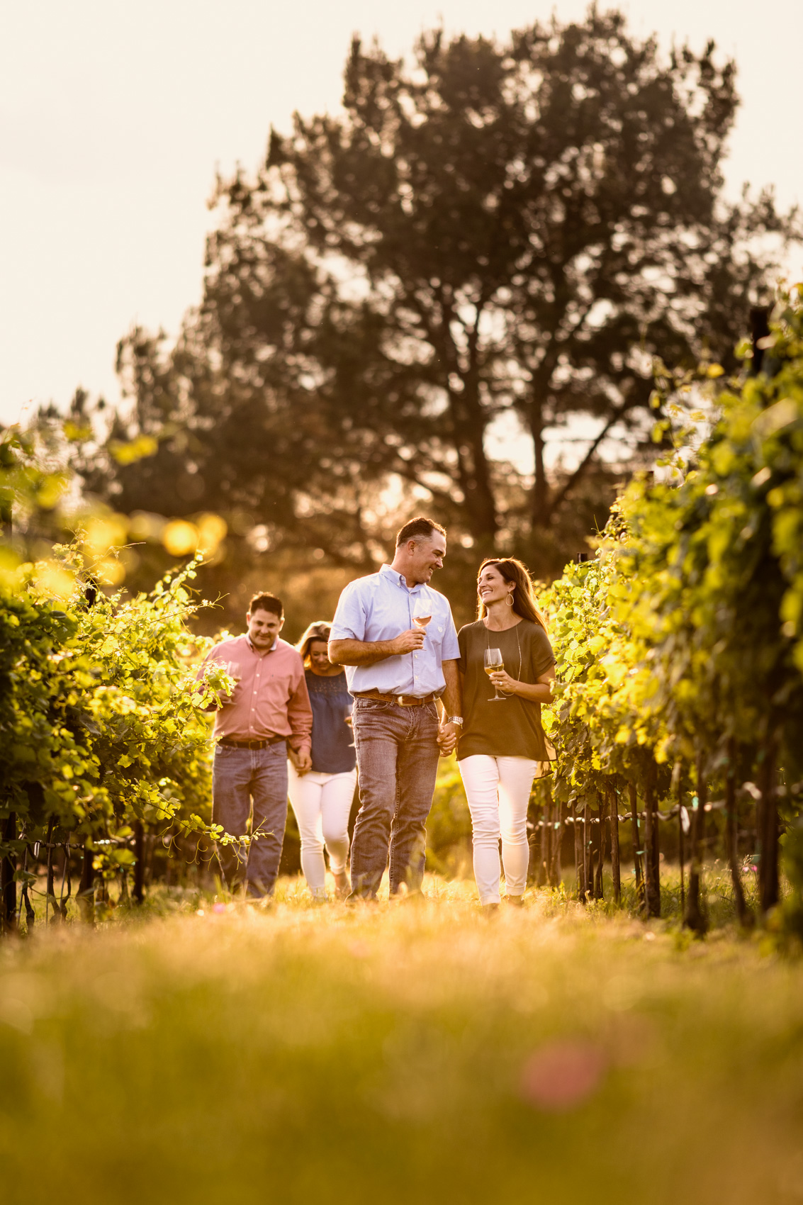 couples walking through vineyard drinking wine in fredericksburg texas