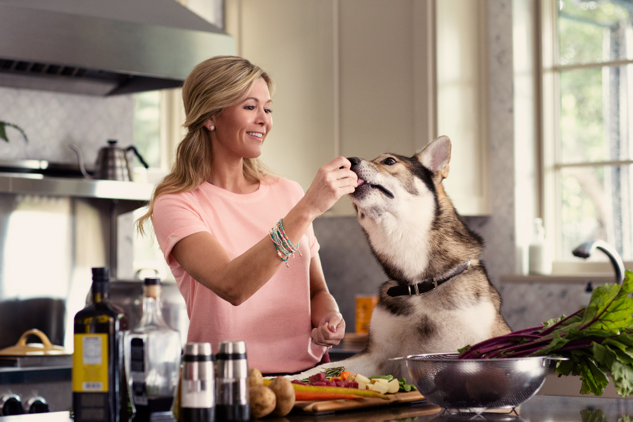 woman in kitchen feeding husky dog