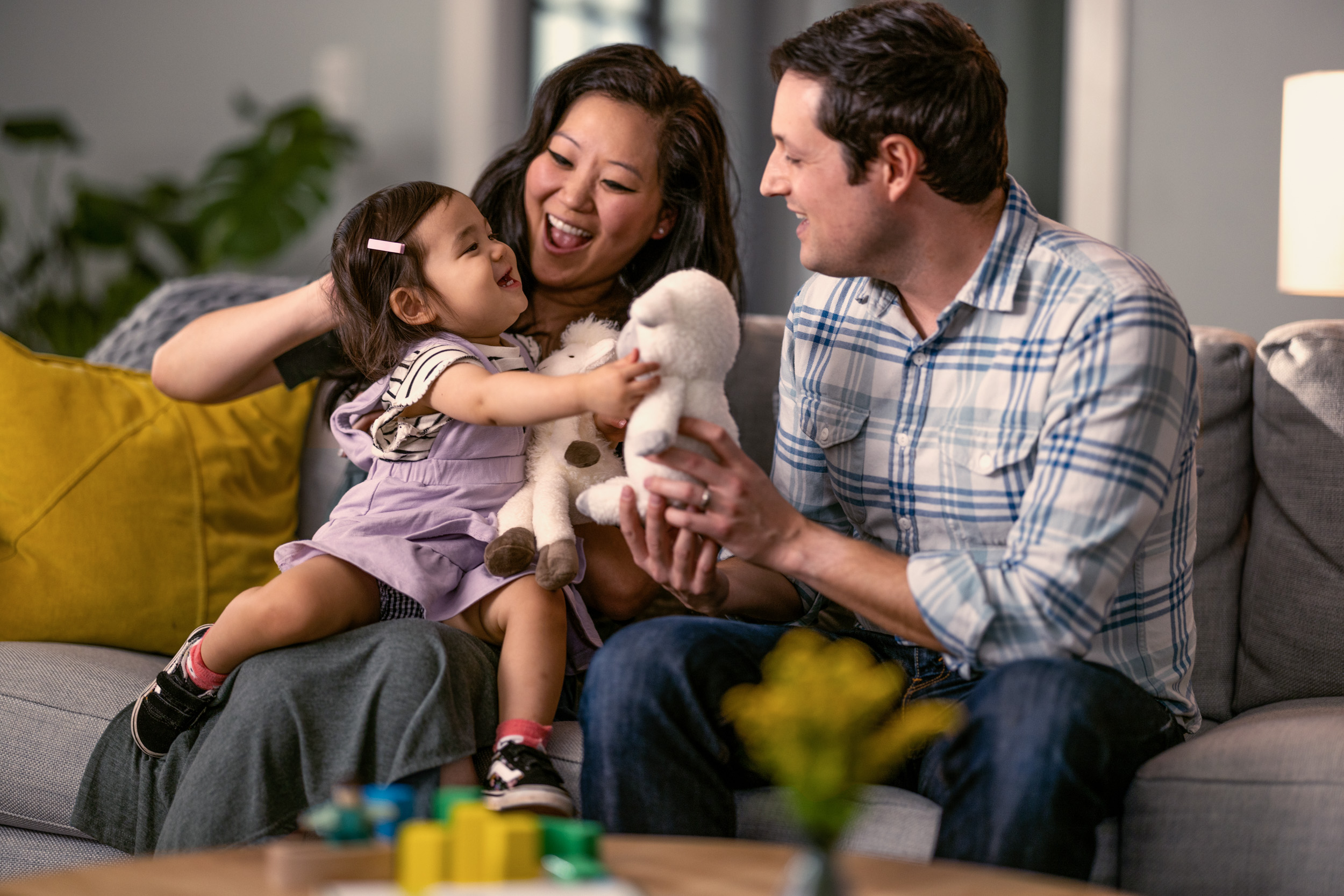 young couple sitting on couch playing with baby