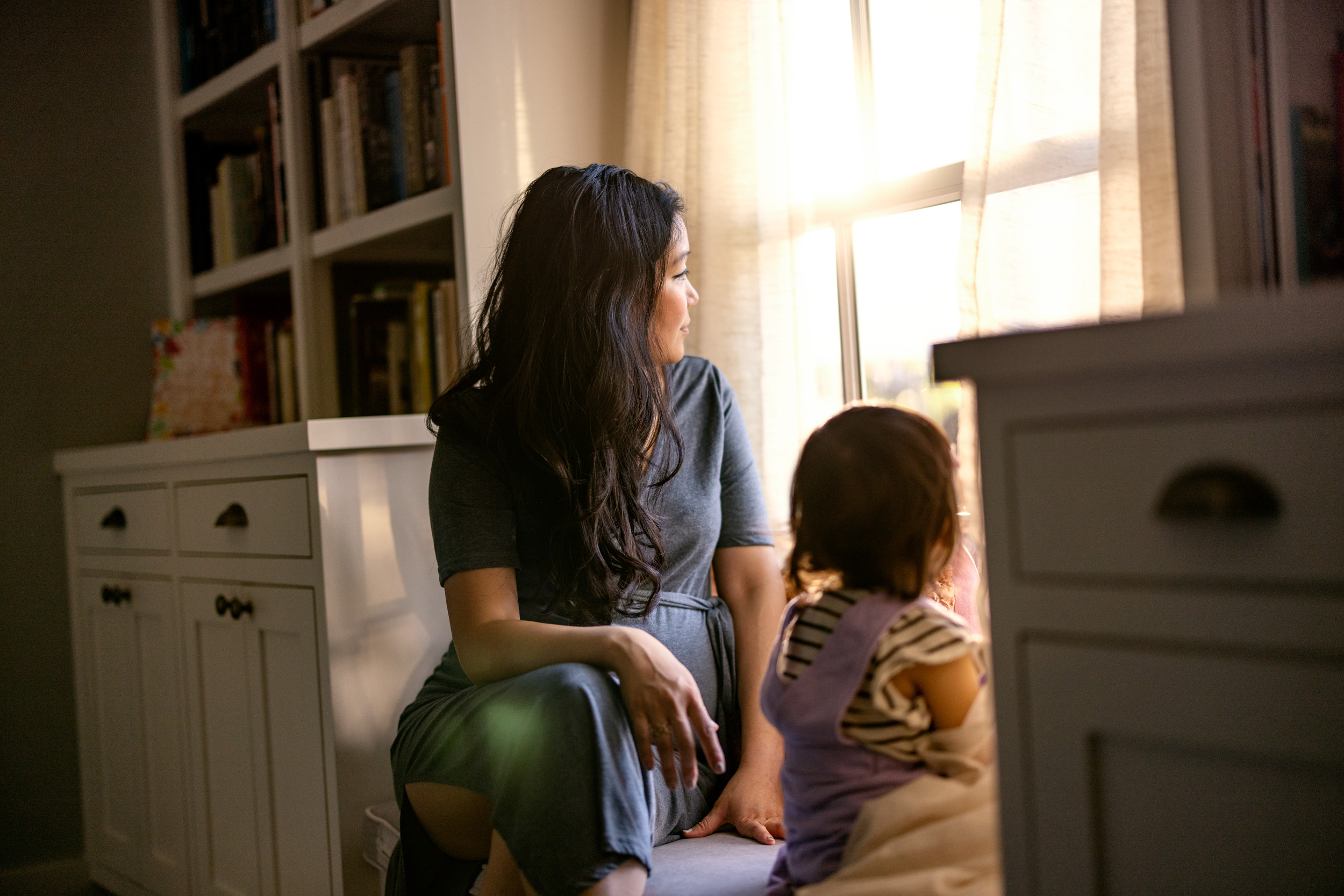 mother and young toddler daughter looking out window