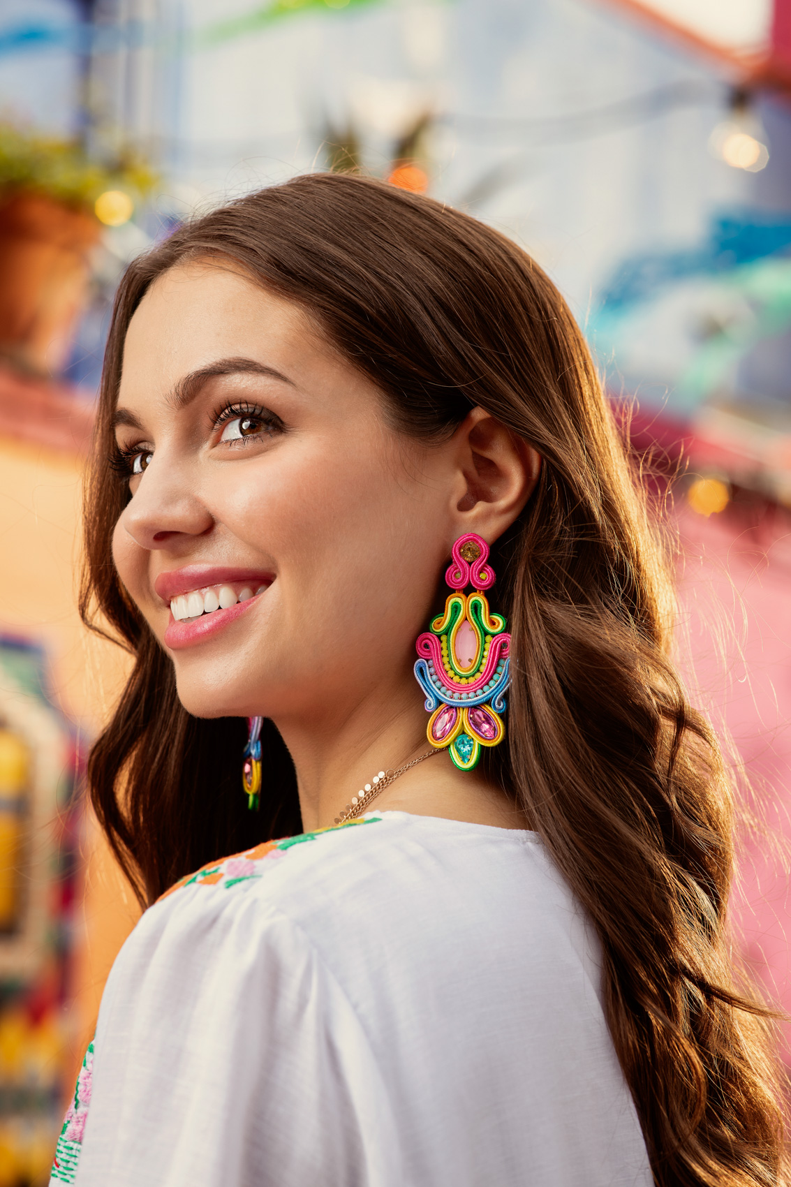 young woman at market square modeling colorful earrings